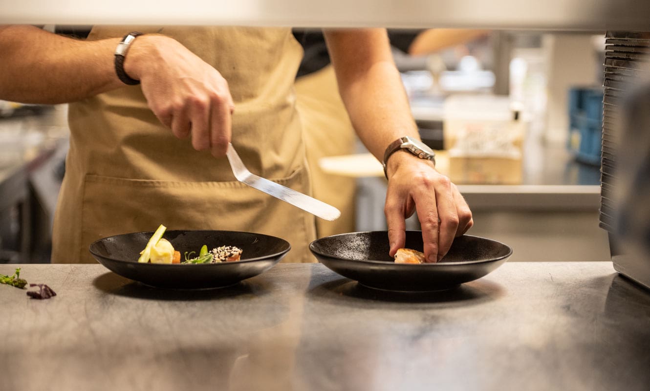 de handen van de chef leggen de laatste hand aan de borden voor hun gasten